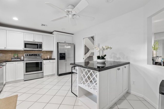 kitchen with white cabinets, stainless steel appliances, tasteful backsplash, kitchen peninsula, and light tile patterned floors