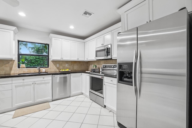 kitchen featuring stainless steel appliances, a sink, visible vents, decorative backsplash, and dark countertops