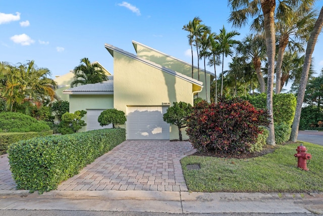 view of front of house with a garage, decorative driveway, and stucco siding