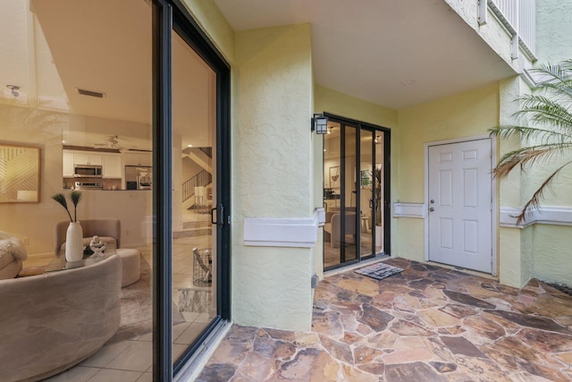 entrance to property featuring visible vents and stucco siding