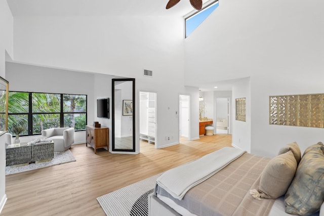 bedroom featuring ceiling fan, visible vents, baseboards, light wood-type flooring, and ensuite bath