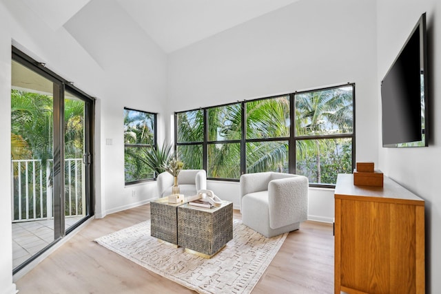 living area featuring light wood-type flooring, baseboards, and lofted ceiling