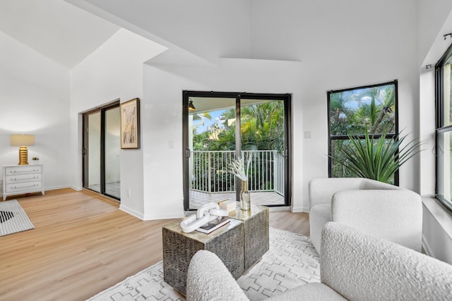 living room featuring light wood-type flooring, baseboards, and a high ceiling