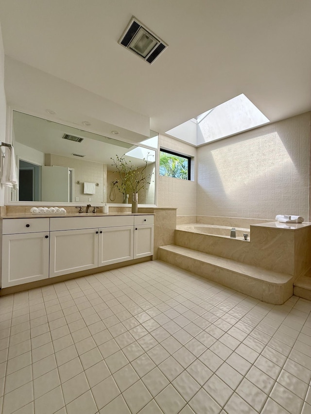 full bath with tile patterned flooring, a skylight, vanity, visible vents, and a bath