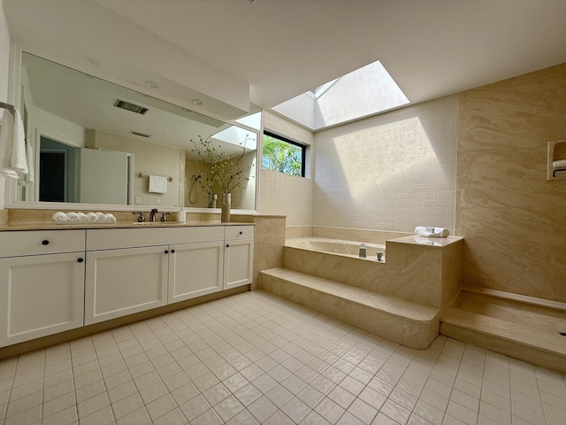 full bathroom with a skylight, visible vents, tile patterned floors, a garden tub, and vanity