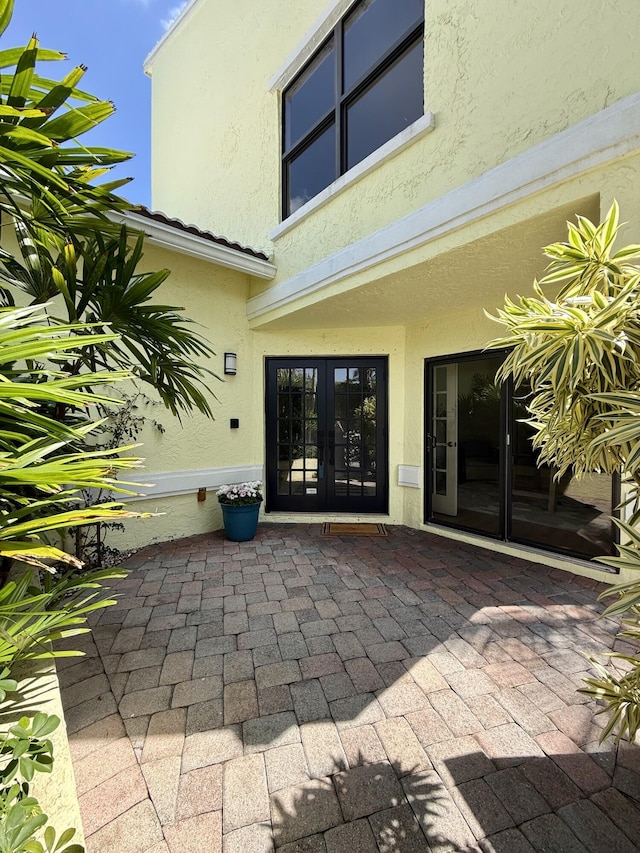 view of exterior entry featuring french doors, a patio area, and stucco siding