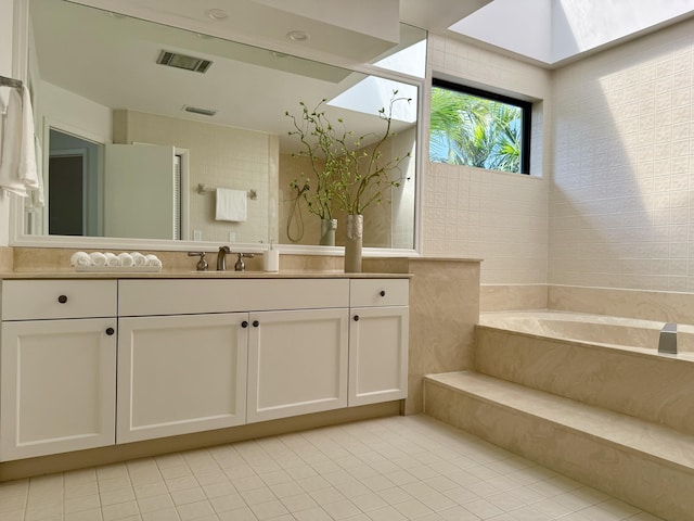 bathroom with vanity, tile patterned flooring, a garden tub, and visible vents