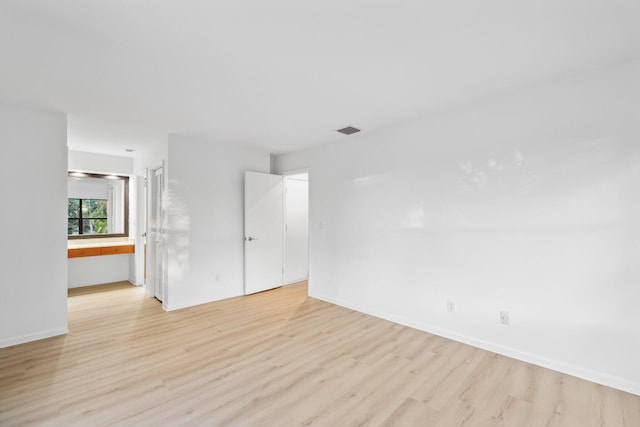 unfurnished room featuring light wood-style flooring, visible vents, and baseboards