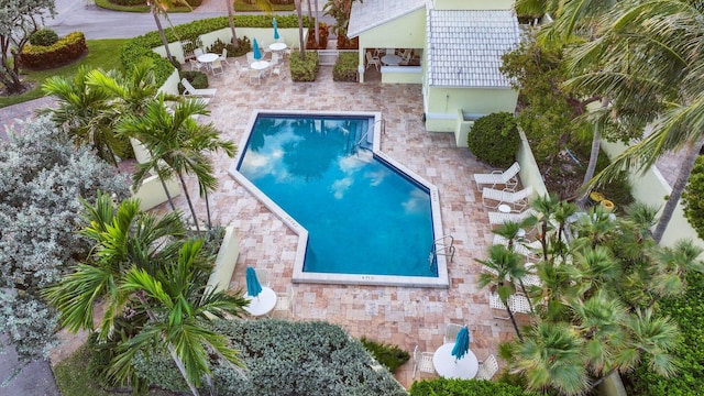 community pool with a patio area, fence, and outdoor dry bar