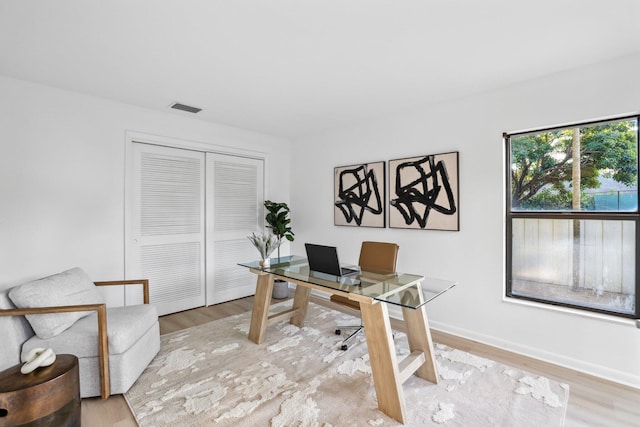 home office featuring wood finished floors, visible vents, and baseboards