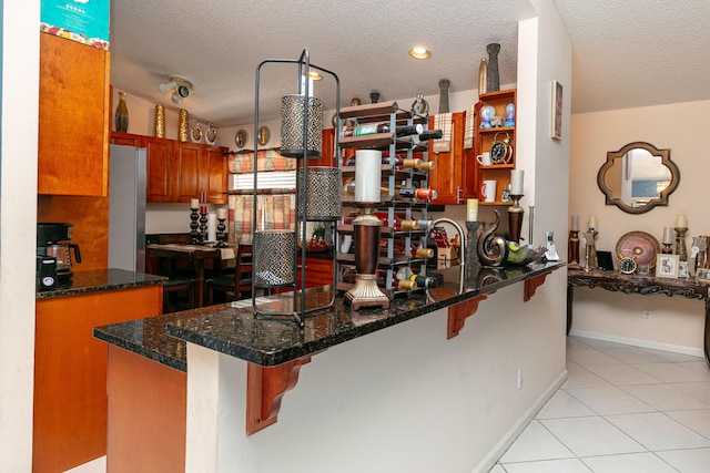 kitchen featuring a textured ceiling, stainless steel refrigerator, and a kitchen bar