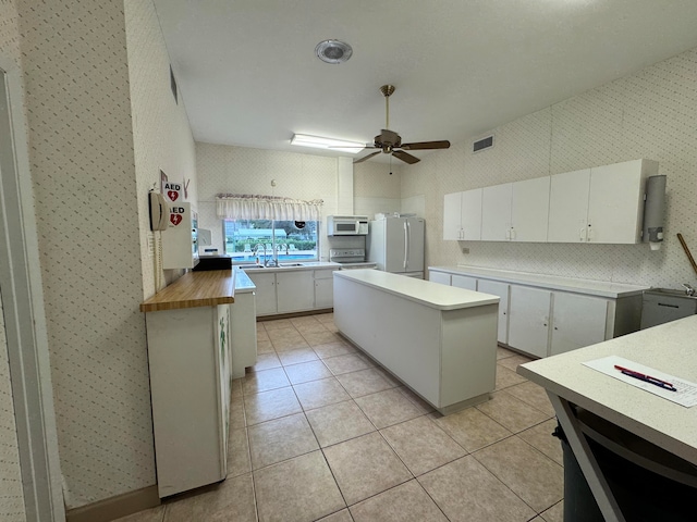 kitchen with white cabinetry, ceiling fan, a kitchen island, white appliances, and light tile patterned floors