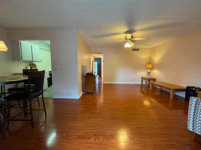 interior space featuring ceiling fan, wood-type flooring, and a textured ceiling