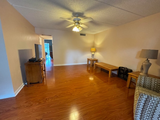 living room featuring ceiling fan, wood-type flooring, and a textured ceiling