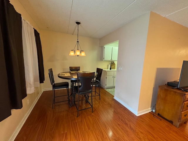 dining area featuring hardwood / wood-style floors, a textured ceiling, and a notable chandelier