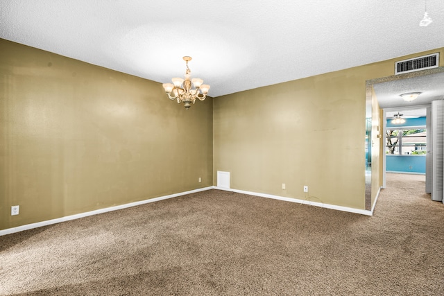 carpeted empty room with a chandelier and a textured ceiling