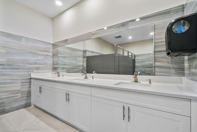 bathroom with vanity, a shower with door, and tile walls