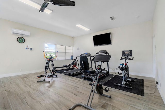 workout area featuring light wood-type flooring and a wall mounted AC