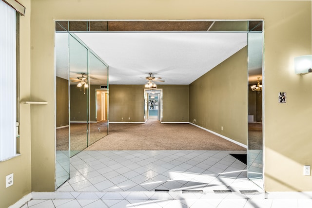 carpeted empty room with ceiling fan with notable chandelier