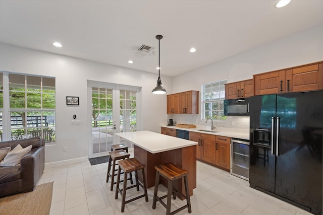 kitchen with decorative backsplash, hanging light fixtures, a kitchen island, a breakfast bar, and black appliances