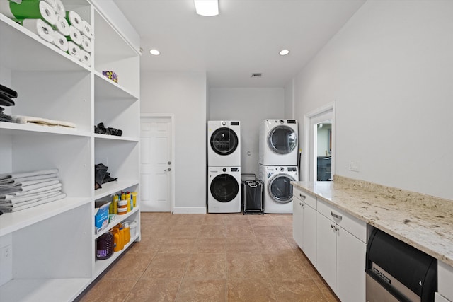 clothes washing area with stacked washer and clothes dryer and light tile patterned floors