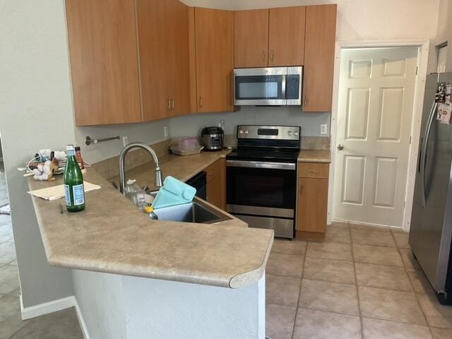 kitchen featuring kitchen peninsula, stainless steel appliances, sink, and light tile patterned floors