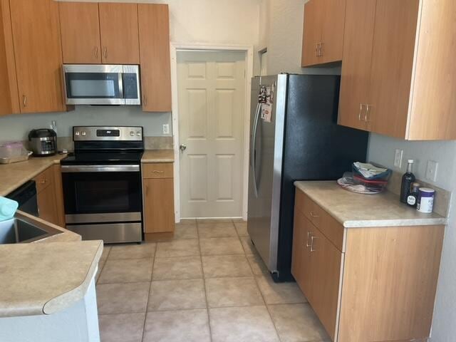 kitchen featuring light tile patterned flooring, stainless steel appliances, and sink