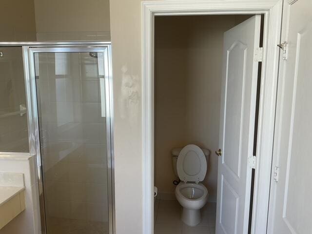 bathroom featuring vanity, toilet, walk in shower, and tile patterned flooring