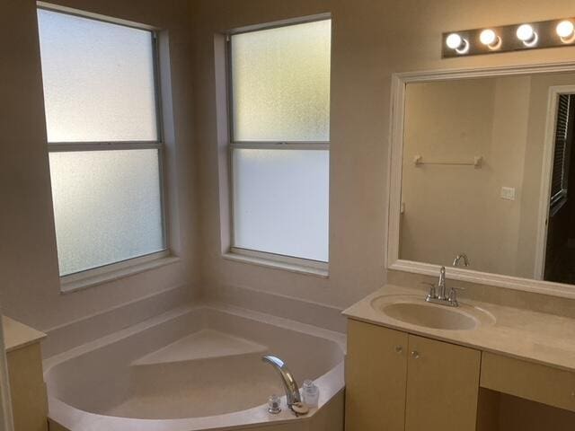 bathroom with a wealth of natural light, vanity, and a tub