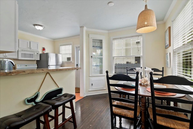 dining space with ornamental molding and dark hardwood / wood-style flooring