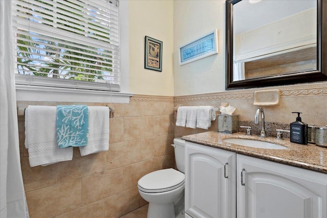 bathroom featuring tile walls, vanity, and toilet