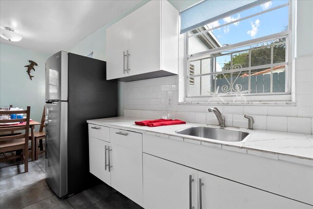 kitchen featuring sink, stainless steel fridge, white cabinetry, and tasteful backsplash