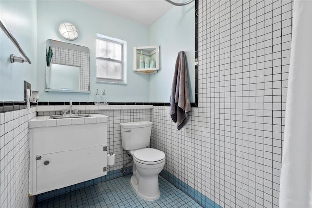 bathroom with tile walls, vanity, toilet, and tile patterned floors