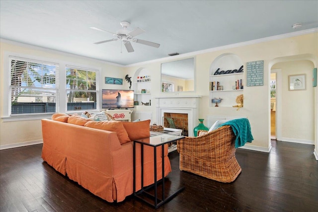 living room with crown molding, ceiling fan, built in features, and dark hardwood / wood-style flooring