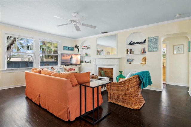 502 39th St, West Palm Beach, FL 33407 - living room featuring arched walkways, crown molding, a fireplace, built in shelves, and dark wood-type flooring