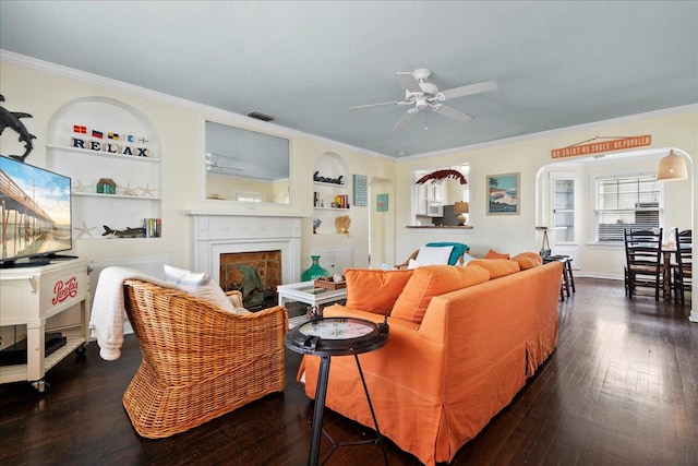 living room with ceiling fan, crown molding, dark hardwood / wood-style flooring, and built in shelves