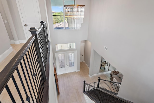 entrance foyer with french doors, light hardwood / wood-style floors, an inviting chandelier, and a high ceiling