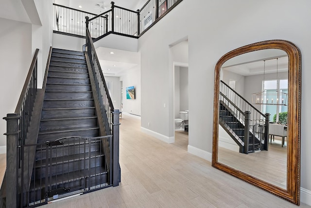 stairway featuring a towering ceiling, an inviting chandelier, and hardwood / wood-style floors