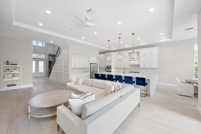 living room featuring a tray ceiling, light hardwood / wood-style floors, and ceiling fan