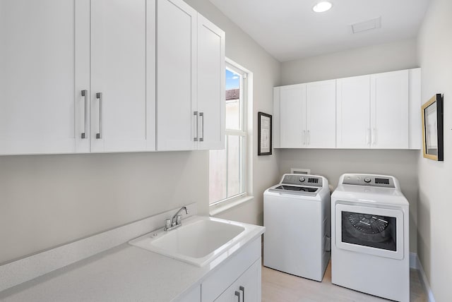 washroom featuring cabinets, sink, washer and clothes dryer, and light hardwood / wood-style floors