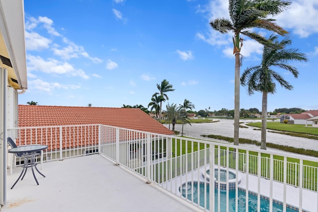 balcony with an in ground hot tub and a water view