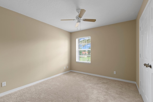 spare room featuring light carpet, a textured ceiling, and ceiling fan