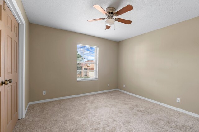 carpeted spare room with ceiling fan and a textured ceiling