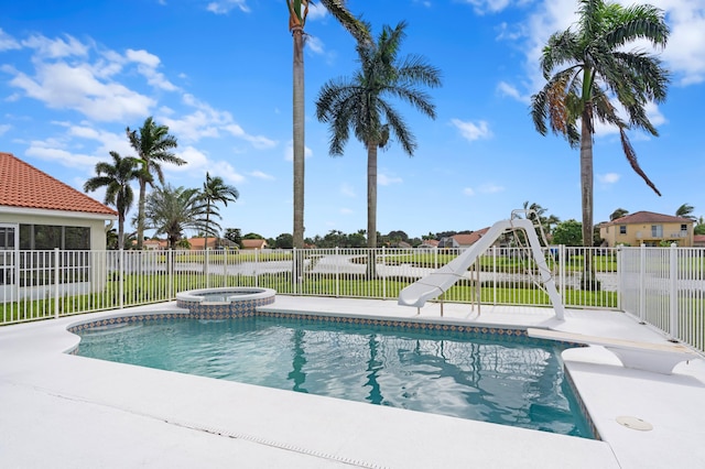 view of swimming pool with a water slide and an in ground hot tub