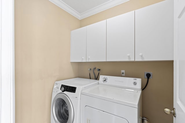 clothes washing area featuring cabinets, crown molding, and washer and dryer