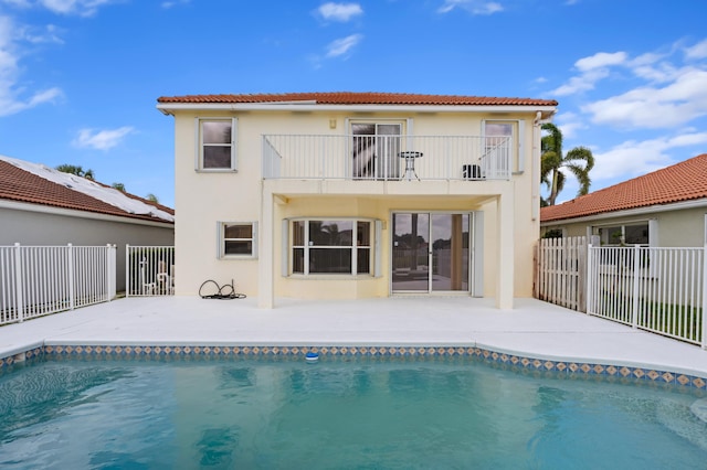 back of house with a patio area, a fenced in pool, and a balcony