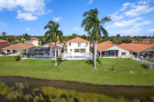 rear view of house with a yard, a patio, a water view, and glass enclosure