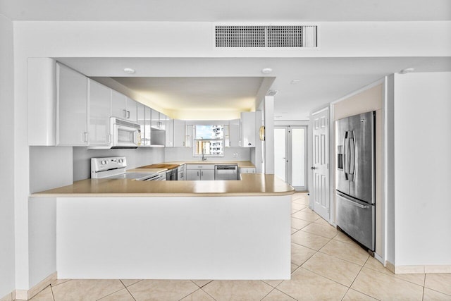 kitchen with white cabinetry, stainless steel appliances, light tile patterned floors, and kitchen peninsula