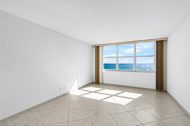 tiled spare room with floor to ceiling windows and a water view