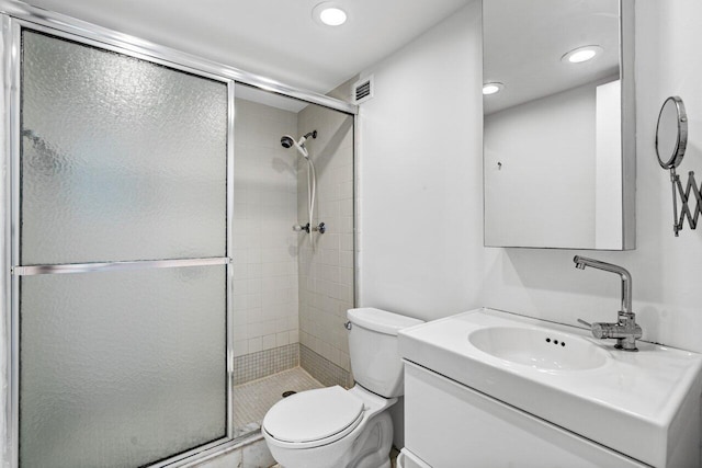 bathroom with toilet, vanity, and a shower with door